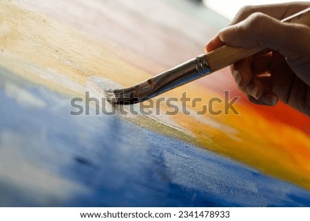 Close up woman hand artist in the darkroom warm light working on painting with brush and variant acrylic color. Female artist painter on canvas in creative studio as art concept Royalty-Free Stock Photo #2341478933