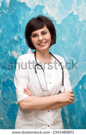 Portrait of a female doctor 40-44 years old near a blue wall. Royalty-Free Stock Photo #2341480891