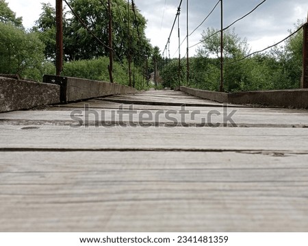 Wooden suspension bridge. Wooden transition from old boards damaged by time and natural conditions, which are attached to a metal base. Royalty-Free Stock Photo #2341481359