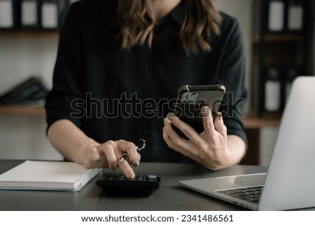 Female businessman working on desk office with using a calculator to calculate cost business report talk smart phone on office desk, finance accounting concept. Royalty-Free Stock Photo #2341486561