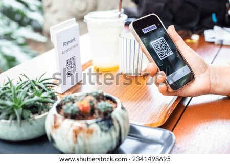 Customer hand using smart phone to scan Qr code payment tag with blur coffee on wooden table to accepted generate digital pay without money. Qr code payment concept.