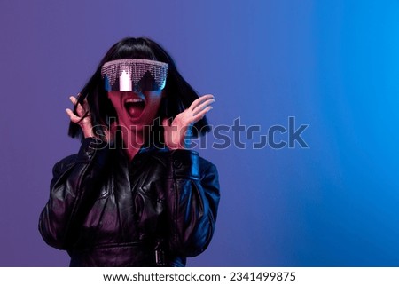 Crazy pretty awesome brunet woman in leather jacket trendy specular sunglasses scream spread hands posing isolated in blue violet color light background. Neon party Cyberpunk concept. Copy space