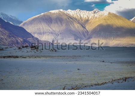 Barren Mountain Landscape view with White Sand Desert and Dramatic clouds. Image of High altitude cold desert of Hunder , Nubra Vallley  , Ladakh ,India Royalty-Free Stock Photo #2341504017