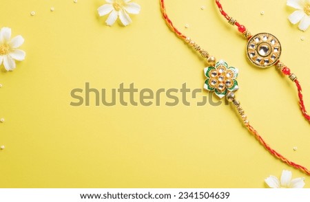 Raksha Bandhan, Indian festival with beautiful Rakhi and Rice Grains on yellow background. A traditional Indian wrist band which is a symbol of love between Sisters and Brothers Royalty-Free Stock Photo #2341504639
