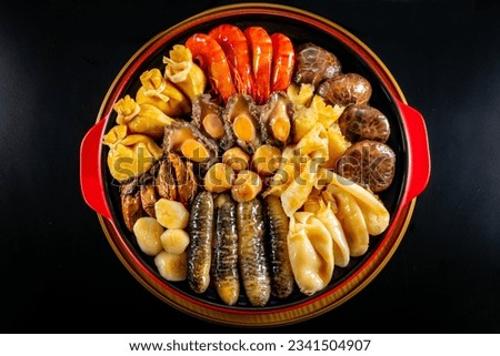 traditional asian luxury treasure premium seafood Peng cai abalone, sea cucumber, scallop, prawn, oyster, mushroom in hot clay pot on red table for Chinese new year cuisine halal banquet food menu Royalty-Free Stock Photo #2341504907