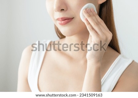 Happy beauty, attractive asian young woman, girl looking camera hand holding cotton pad, applying facial wipe on her face remover makeup, essence or lotion of skin care. Isolated on white background. Royalty-Free Stock Photo #2341509163