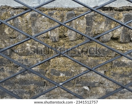 Nice rhombus iron fence texture against mossy brick background