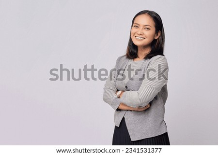 Satisfied smiling happy successful young Asian employee businesswoman looking at the camera with confidence while crossed hands isolated on grey background studio portrait