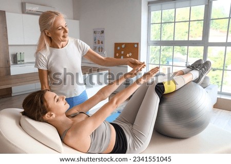 Female physiotherapist working with young woman on couch in rehabilitation center Royalty-Free Stock Photo #2341551045