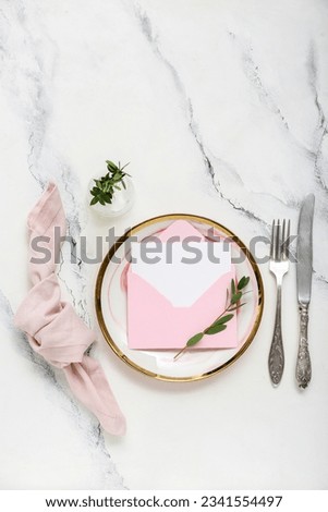 Stylish table setting, envelope with blank card and vase of plant branch on grunge white background