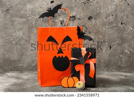 Composition with shopping bag, gift box and bats for Halloween on grunge grey background
