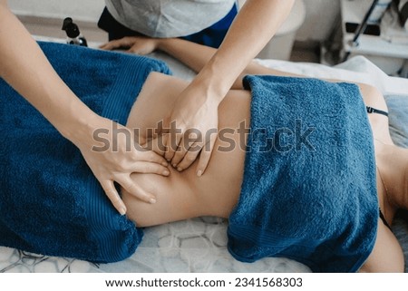 masseur doing massage of the muscles. the hands of a masseur do massage the abdomen closeup. photos for advertising massage services. anti-cellulite massage close-up.