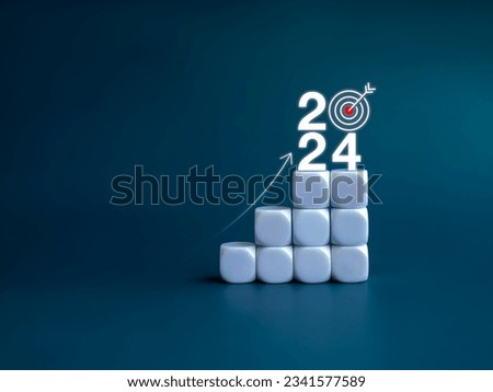2024 year number with target icon and rise up arrow on white blocks as a graph steps on blue background. New year trends, action plan, profit, business growth process, economic improvement concepts.