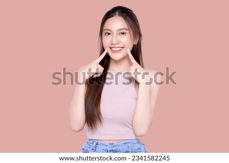 Beautiful young Asian woman pointing finger to her teeth on isolated pink background. Facial and skin care concept for commercial advertising. Royalty-Free Stock Photo #2341582245