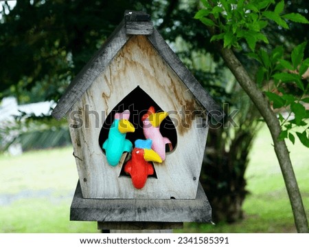 A wooden birdhouse in the garden with colorful plastic ducks in it, cartoon stlye concept.