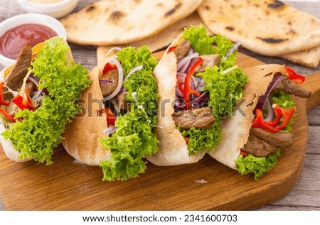 Pita stuffed with chicken, onion and letucce over wooden background, front view