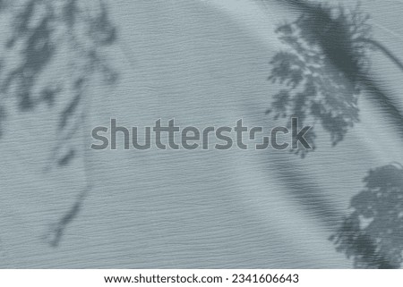 Aesthetic floral neutral pastel blue background with wildflower sunlight shadows on fabric texture. Flower silhouette on a light ice blue backdrop, wedding or business brand template