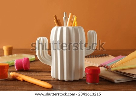 Stylish holder with different stationery on wooden table