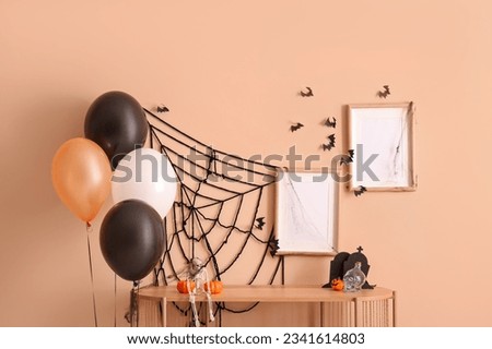 Halloween balloons, shelving unit and blank frames hanging on beige wall in room