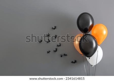 Halloween balloons and bats hanging on grey wall in room