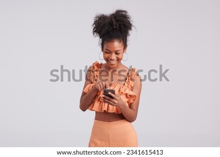 Adding smartphone glamour to the mix, a girl in an orange shirt perfects her studio pose, capturing her fashionable look with finesse.