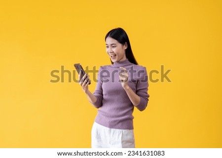 A pretty Asian woman is using her smartphone, chatting, sending SMS or email, scrolling on social media, updating her blog, using mobile apps, and enjoying online shopping. isolated yellow background