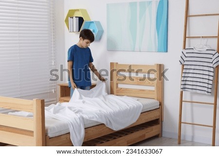 Boy changing bed linens in children room Royalty-Free Stock Photo #2341633067