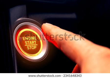 The driver's hand is pressing the car start button. Concept of transportation and technology Royalty-Free Stock Photo #2341648343
