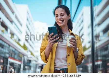 Woman texting and drinking coffee outdoors. Artificial intelligence and communication network concept.Beautiful young woman using a smartphone.  Royalty-Free Stock Photo #2341665339