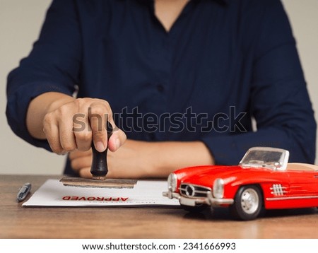 A businessman stamped approved documents for a car loan agreement. Get a car loan for your dream vehicle. Easy application process and fast approval