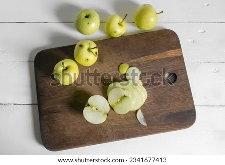 Processing of wormy apples. Spoiled apples with black dots - crop processing. Slicing an apple on a wooden board. Royalty-Free Stock Photo #2341677413