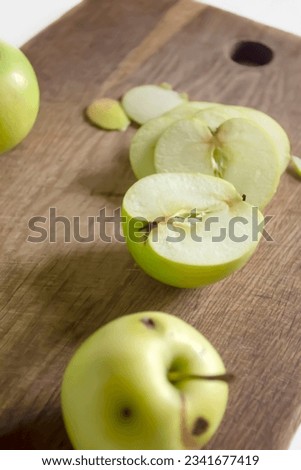Processing of wormy apples. Spoiled apples with black dots - crop processing. Slicing an apple on a wooden board. Royalty-Free Stock Photo #2341677419