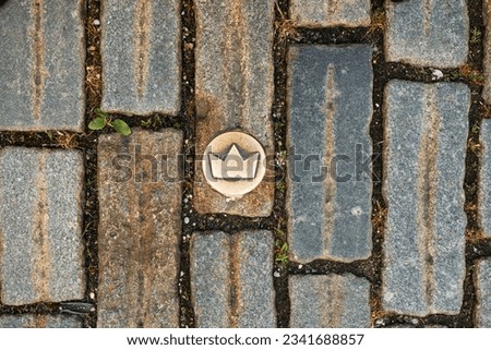 Slovakia, Bratislava. Brass crown marker in cobblestone streets show location of the coronation walk. Old town. Top view of brass crown marker in cobblestone streets