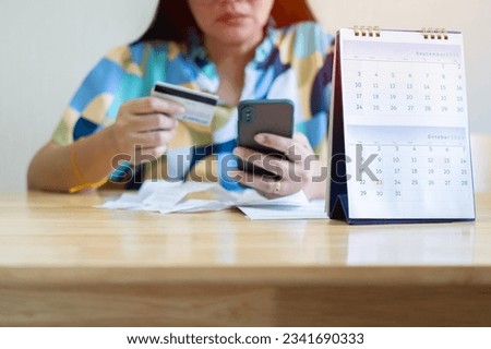 Due date calendar with blur business Asian woman  holding a credit card and calculating monthly expenses during tax season. Royalty-Free Stock Photo #2341690333