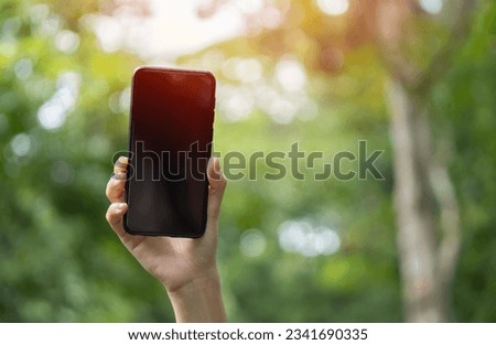 Young woman hand with smartphone catching signal at wooden forest. Road trip, transport, travel, technology and people concept