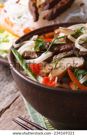 Asian food: rice noodles with shiitake, meat and vegetables in a bowl. Vertical close-up 