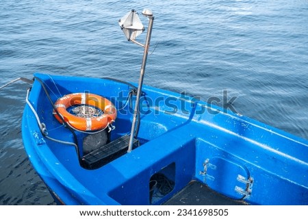 Fragment of a wooden blue fishing boat, orange lifebuoy