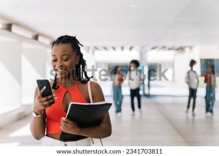 Young student using his mobile phone in the university campus. Diversity, inclusion, scholarship, graduation and back to school concept Royalty-Free Stock Photo #2341703811