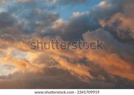 grey clouds with blue sky in the background, coloured with red tones by the last rays of the evening Royalty-Free Stock Photo #2341709919