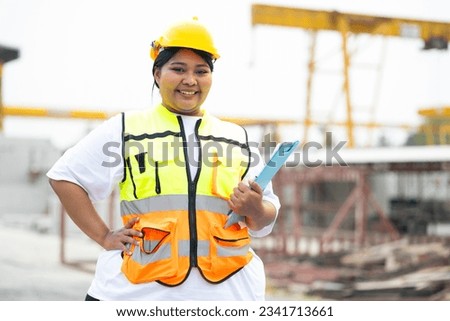 Plus size female factory worker wearing safety hard hat helmet working at heavy Prefabricated concrete walls manufacturing factory. Portrait African american woman Royalty-Free Stock Photo #2341713661