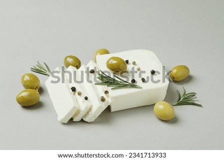 Feta cheese, olives, rosemary and pepper on gray background