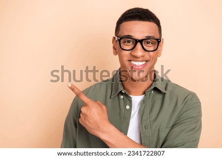 Photo of positive friendly guy toothy smile indicate finger empty space novelty ad isolated on beige color background