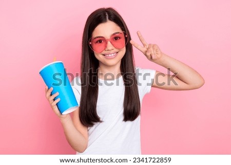 Photo portrait of adorable schoolkid female showing v-sign plastic cup glasses wear trendy white outfit isolated on pink color background
