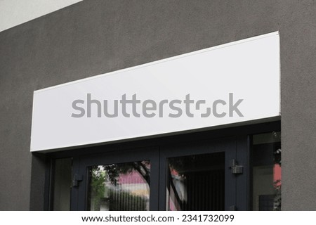 Blank white shop sign mockup, large billboard banner on a storefront mock up template. Royalty-Free Stock Photo #2341732099