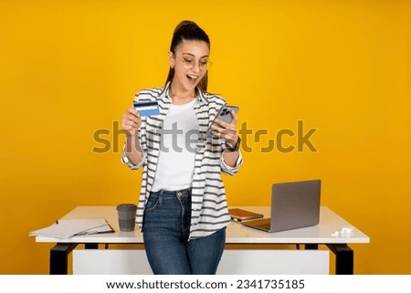 Business woman holding credit card, young surprised amazed caucasian employee business woman holding credit card. Looking mobile cell phone. Online shopping, order meal, book tour. Career concept.