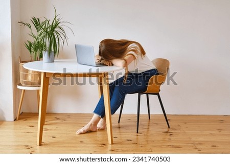 A young girl fell asleep in front of a laptop. Pretty woman is tired or overworked. Cozy home environment