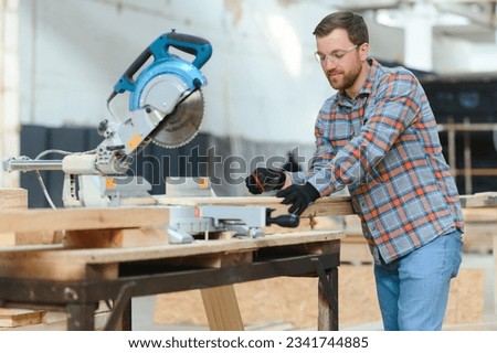 Skilled cabinet maker cutting wood board with electric circular saw at woodworking sawmill. Professional cabinet maker use circular saw at sawmill factory. Wooden furniture production Royalty-Free Stock Photo #2341744885
