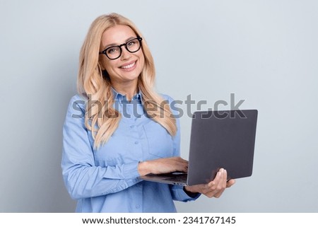Photo of mature cheerful business woman professional broker hold netbook writing resume find new vacancy isolated on grey color background