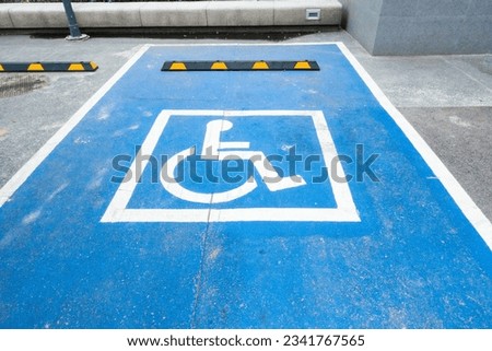 International handicapped symbol painted in bright blue on a shopping center parking space,Disabled parking sign, road traffic signs.