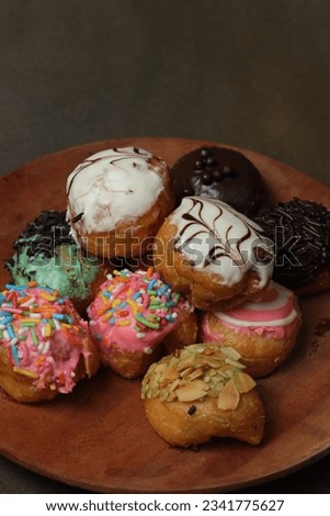 colorful donuts with various flavors on a brown wooden plate.  suitable as a commercial photo